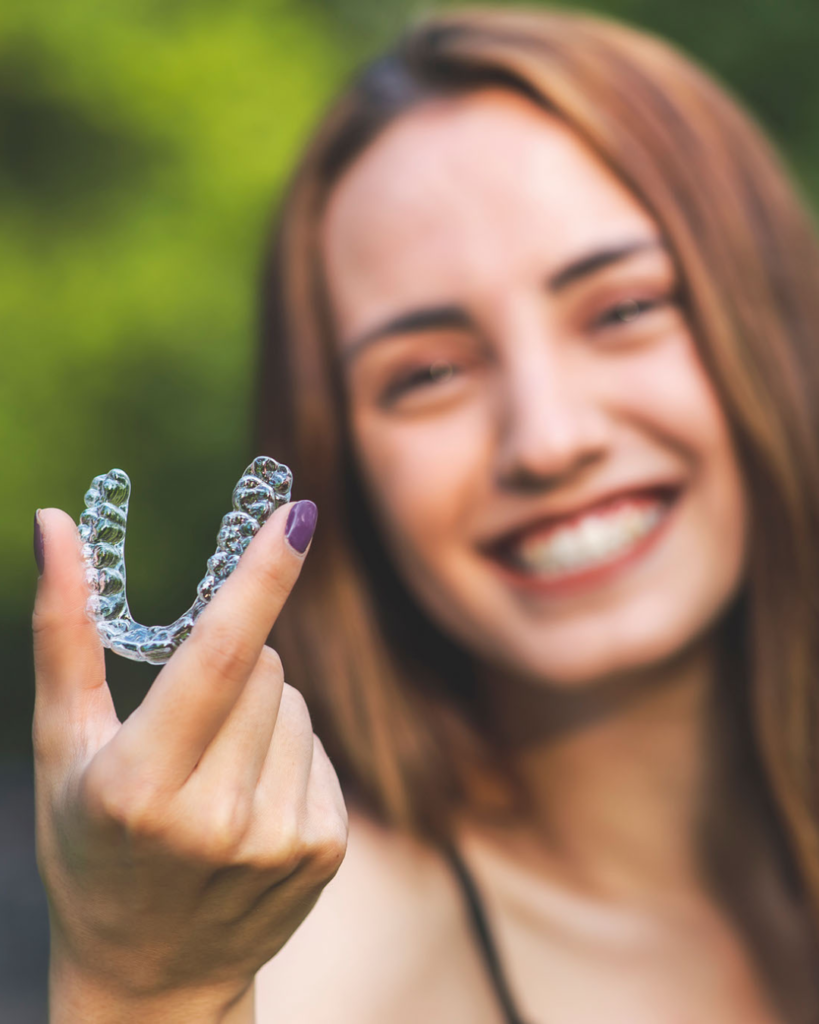 A young girl is holding Invisalign trays in Woodland Hills.